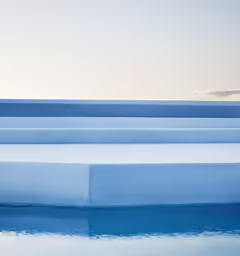 four identical, white benches are sitting next to a pool