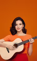 a woman wearing an orange dress and holding a guitar