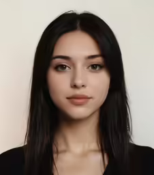 woman in black shirt posing for photo next to white wall