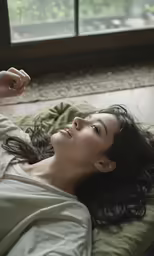 a woman lies on the bed with her hands over her head