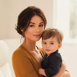 a woman holding a child and posing for the camera