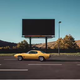 a yellow car in a parking lot with a sign in the background