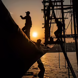 two people working on a ship at sunset