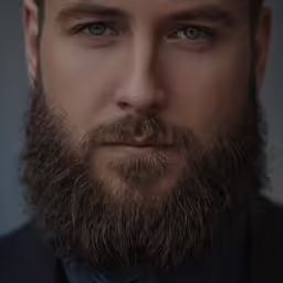 a close up of a person with a beard and wearing a tie