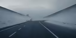 a street with white lines through a foggy valley