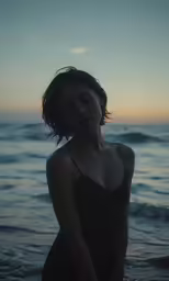 a woman stands in the water on the beach