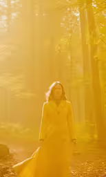 a woman is walking in the woods with sunlight coming down on her