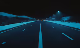 a snowy road at night with snow covered ground