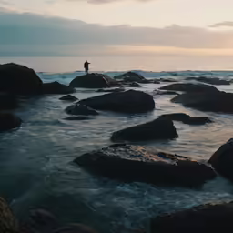 the person is standing on rocks above the water