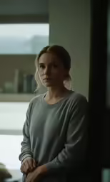 a woman standing by a window in an empty room