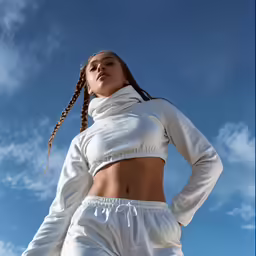 a woman wearing white pants and crop top