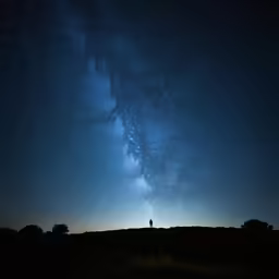 there is a lone man standing in the field under stars