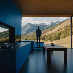 there is a man standing at a balcony looking over mountains
