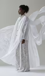 a woman in white stands and looks off to the side
