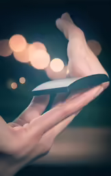 a hand holding a black object in front of lots of lights