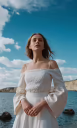a woman in a white dress is standing by the water