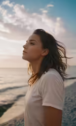 a woman standing on a beach near the ocean