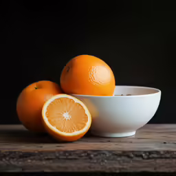 a bowl with half an orange and one side are on a wooden table