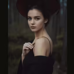 a young girl is wearing a black hat and standing in the woods