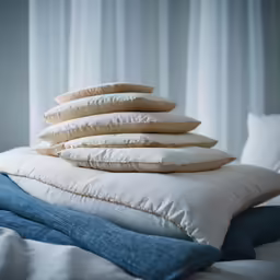 a pile of pillows sitting on top of a bed