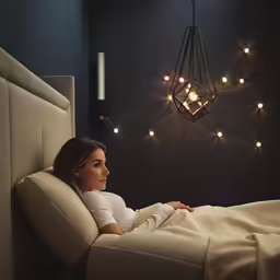 a woman laying on her side under the covers of a bed in the room
