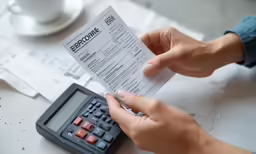 a persons hand is holding a check while they fill out the receipt