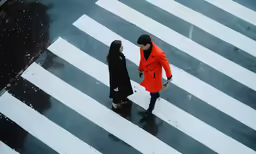 an aerial view of two people walking on an asphalt crosswalk