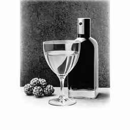 the glass next to the bottle of wine is near a blackberry