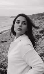 a woman in a white top poses by the water