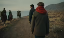 three people with red scarf on riding horses along a trail
