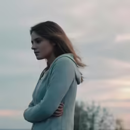 the girl is standing outside by the water