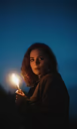 woman holding a lighter lit up in the dark