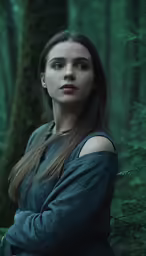 a young woman standing in front of a forest