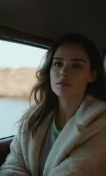 a woman sitting on the side of a vehicle while wearing a robe
