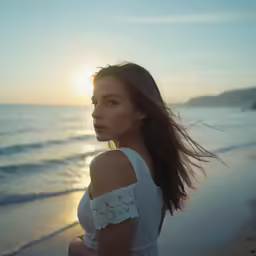 a woman standing on top of a beach near the ocean