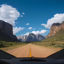 the view from inside a car of mountains and a dirt road
