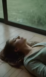 a beautiful young woman lying on the ground near a window