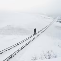 the man is walking on a boardwalk in the snow