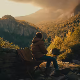 a person sitting on a chair looking down at a mountain valley