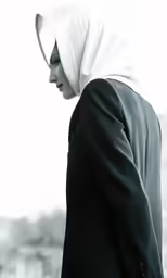 an arabic woman in a black jacket and white turban is walking