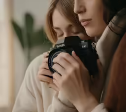 the two women are holding a camera close together