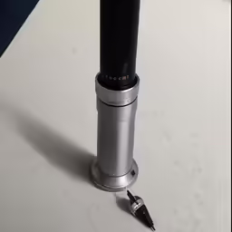 an old silver and black pen is on a white surface
