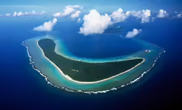 an aerial view of a small island that is surrounded by clouds