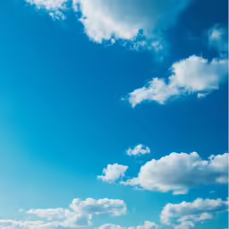 a beach with umbrella and people sitting under blue cloudy sky