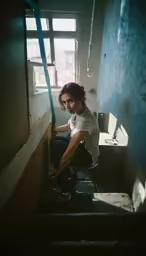 a girl sits on some stairs near the window