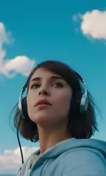 a woman with headphones on stares into the sky
