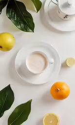 a table with lemons, oranges and saucer and coffee