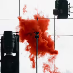 a photo camera and red smoke are shown