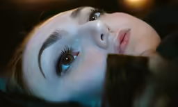 a woman with blue eyes laying on top of a couch