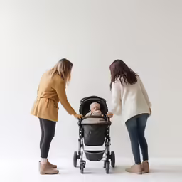 two ladies are pushing on a child in a baby seat